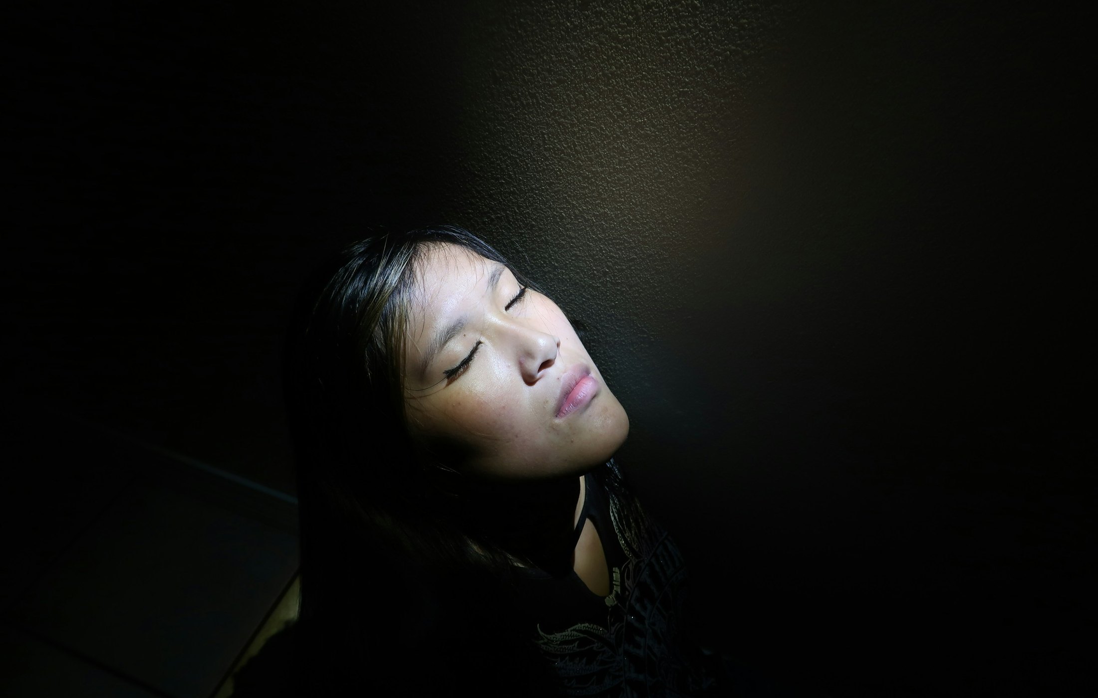 薄暗い部屋で目を閉じて休んでいる様子